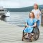 A woman in a wheelchair walks with her sister on a wooden pier by the sea