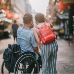 Men in wheelchair with female friend in the street taking selfie