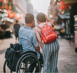 Men in wheelchair with female friend in the street taking selfie