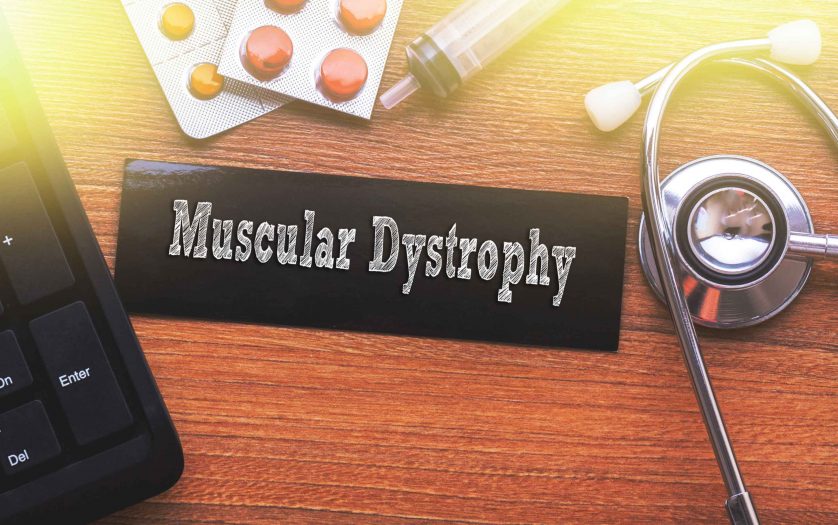 MUSCULAR DYSTROPHY words written on label tag with medicine,syringe,keyboard and stethoscope with wood background