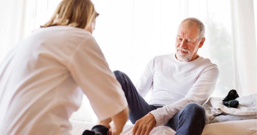 Health visitor and senior man during home visit.