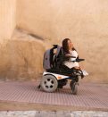 woman in electronic wheelchair geeting out from the building