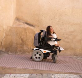 woman in electronic wheelchair geeting out from the building