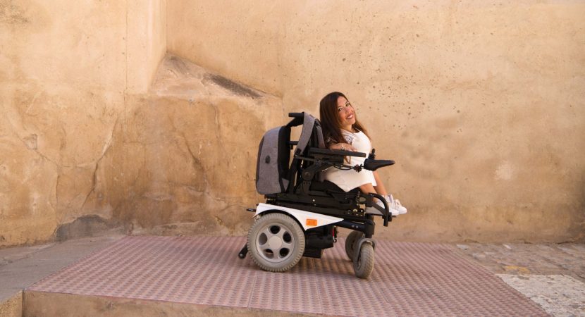 woman in electronic wheelchair geeting out from the building