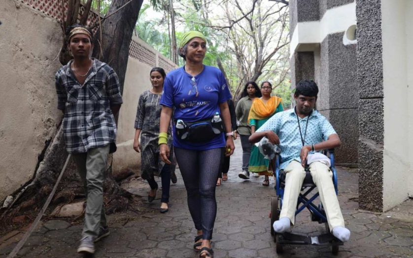 Gita walking with people, in her right side a person in wheelchair