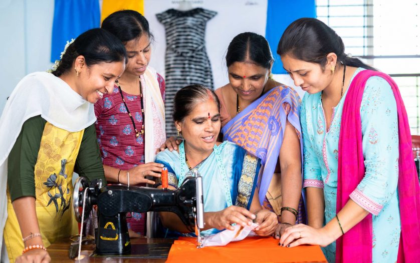 roup of woman at tailoring class discuissing with teacher about cloth and stitching during training