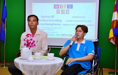 A person in a wheelchair speaking during a training session with another person seated next to them on the left.