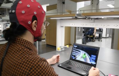 Hussein Alawieh, a graduate student in Dr. José del R. Millán's lab, wears a cap packed with electrodes that is hooked up to a computer. The electrodes gather data by measuring electrical signals from the brain, and the decoder interprets that information and translates it into game action.