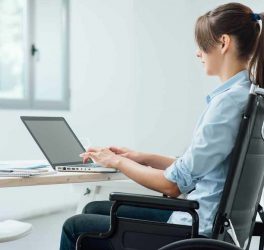 A womn in a wheelchair using a computer
