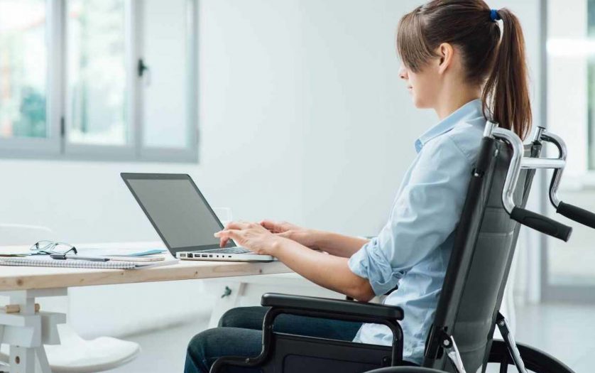 A womn in a wheelchair using a computer