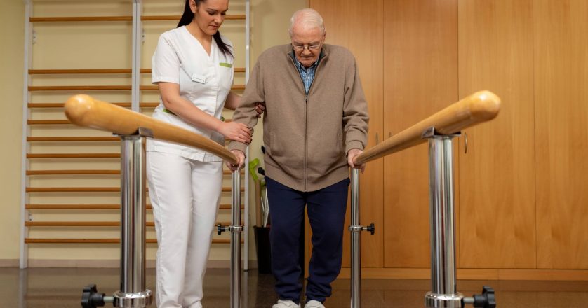 nurse helping elderly man walk