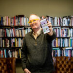 Wichita State Professor Darren DeFrain holding smartphone, showing app