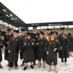 A group of students are standing in graduation caps and gowns at their graduation ceremony.