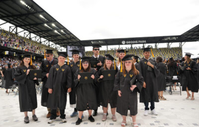 A group of students are standing in graduation caps and gowns at their graduation ceremony.