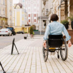 A woman in a wheelchair moves along a city street