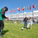 Three people playing soccer, two eyes covered at the Council of Europe park in Belgrade.
