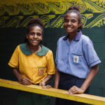 Angela, 13, and Jayme, 15, stand outside the new toilet block at their school in Central Province, Papua New Guinea, April 2024.