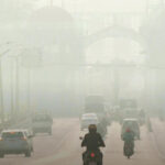 People driving on a city road amid air pollution.
