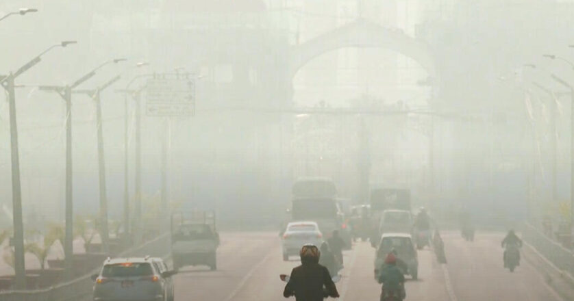 People driving on a city road amid air pollution.