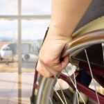 rear view of a man in wheelchair at the airport with focus on hand