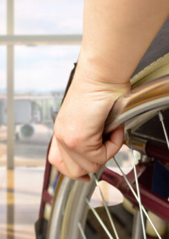 rear view of a man in wheelchair at the airport with focus on hand
