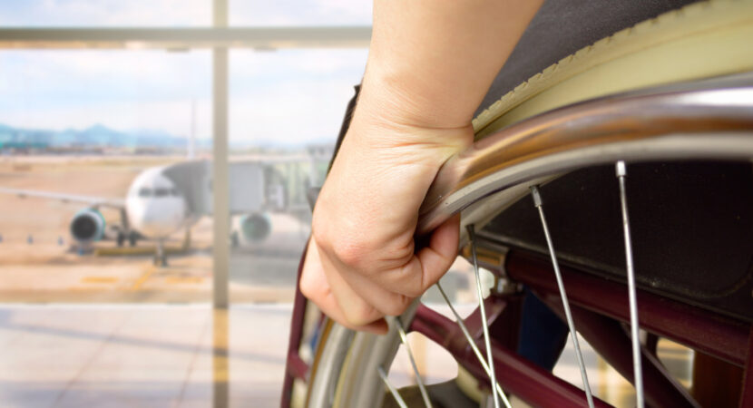 rear view of a man in wheelchair at the airport with focus on hand