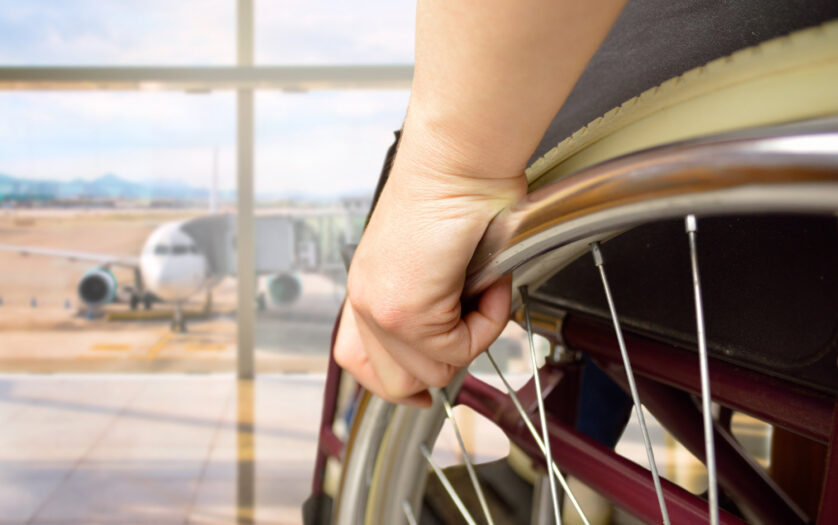 rear view of a man in wheelchair at the airport with focus on hand