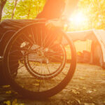 Wheelchair user camping, on the background of tents.