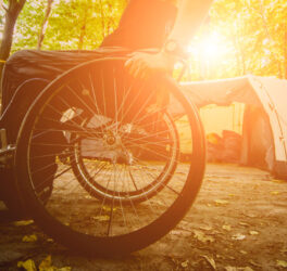 Wheelchair user camping, on the background of tents.