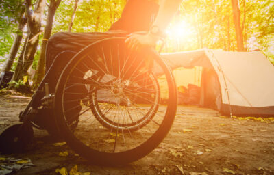 Wheelchair user camping, on the background of tents.