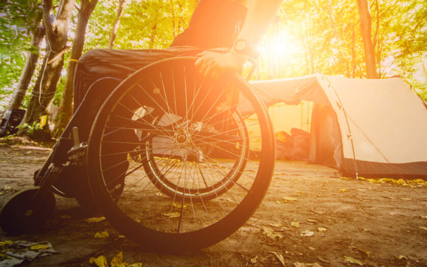Wheelchair user camping, on the background of tents.