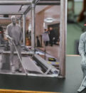 A model of a man with a red had sat on a chair with a white cane next to a photo of a similar figure