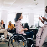 woman in wheelchair talking with her colleague in the office