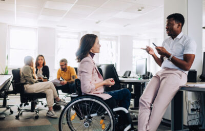 woman in wheelchair talking with her colleague in the office