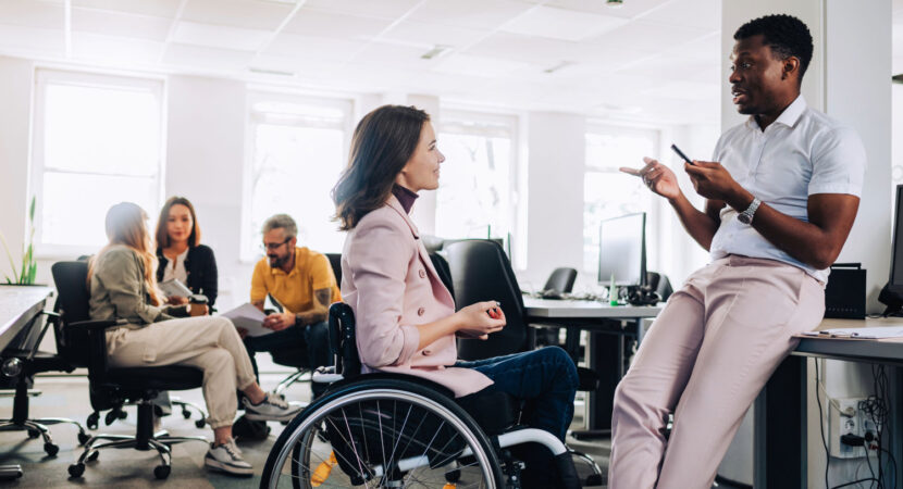 woman in wheelchair talking with her colleague in the office