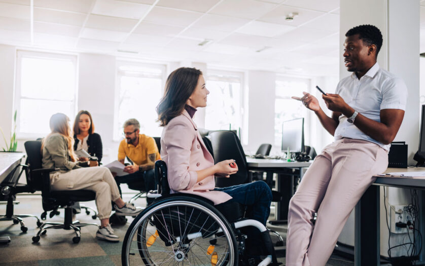woman in wheelchair talking with her colleague in the office