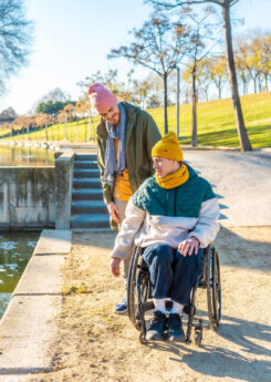 Men in wheelchair with his friend spending time together in the park during a sunny day