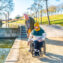 Men in wheelchair with his friend spending time together in the park during a sunny day
