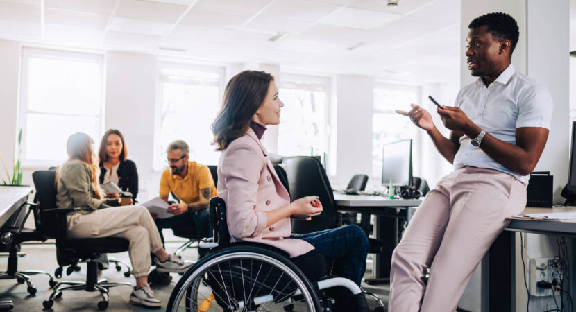 Women in wheelchair talking with her colleage in the office