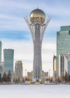 Baiterek Tower in winter, Astana city skyline under bright sky.