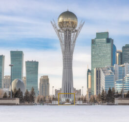 Baiterek Tower in winter, Astana city skyline under bright sky.