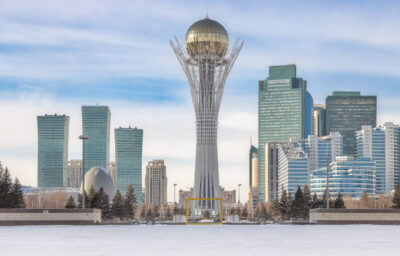 Baiterek Tower in winter, Astana city skyline under bright sky.