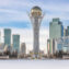 Baiterek Tower in winter, Astana city skyline under bright sky.