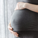 Pregnant woman staying and touching her belly. Enjoying pregnancy.