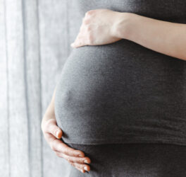 Pregnant woman staying and touching her belly. Enjoying pregnancy.