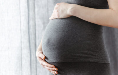 Pregnant woman staying and touching her belly. Enjoying pregnancy.
