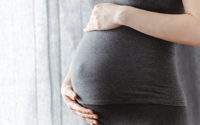 Pregnant woman staying and touching her belly. Enjoying pregnancy.