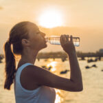 woman drinking water outdoor on sunny day.