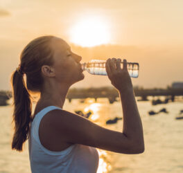 woman drinking water outdoor on sunny day.