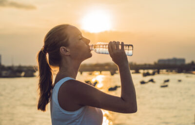 woman drinking water outdoor on sunny day.